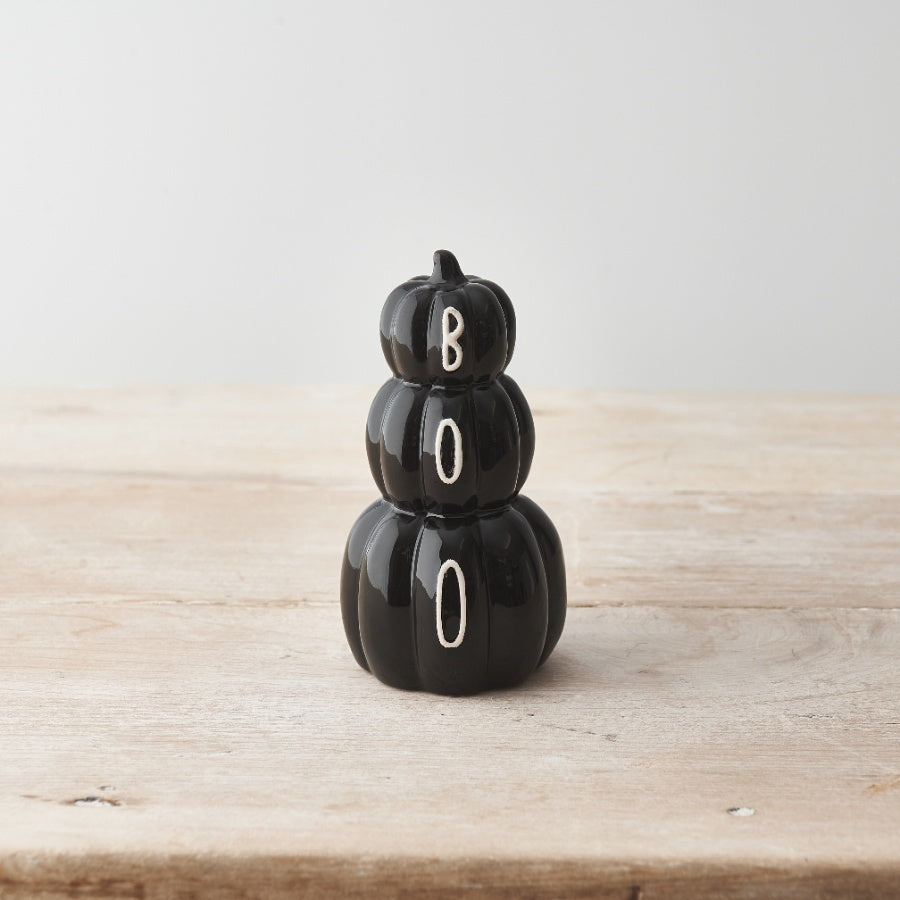 Glossy black ceramic stacked pumpkins spelling BOO on a wooden surface