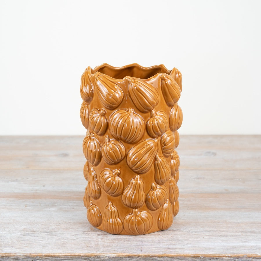 Amber ceramic vase with all-over embossed pumpkin and gourd relief on a wooden surface