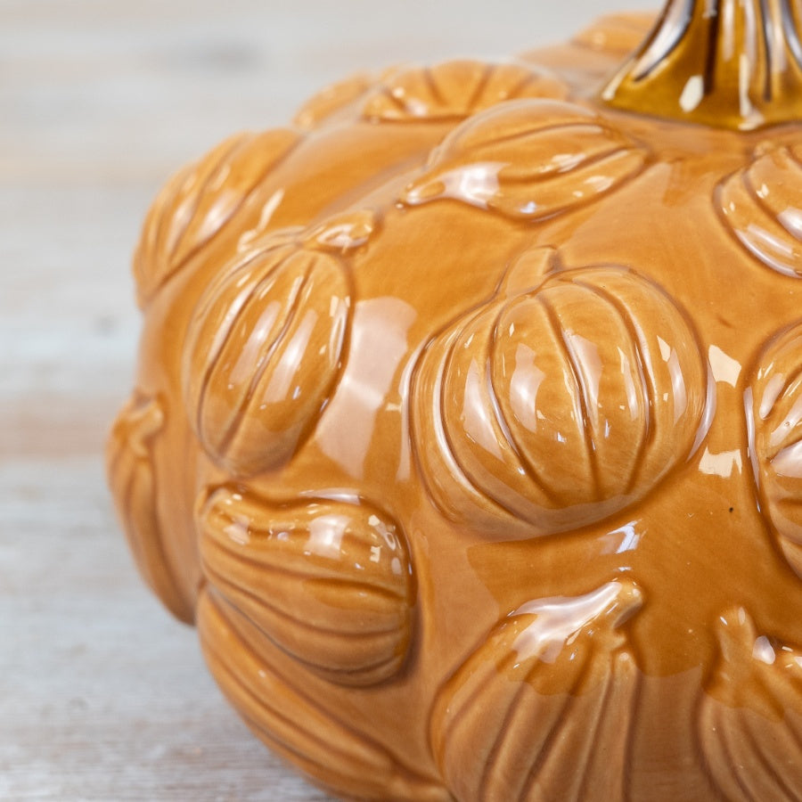 Close-up of embossed miniature pumpkin relief detail on glazed amber ceramic pumpkin ornament
