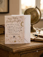 Happy Birthday Darling Daughter card — cream verse card with gold stars and moon charm, warm study lifestyle photo with globe and fountain pen