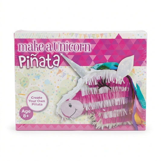 A person holding a shrink-wrapped craft kit box labeled 'make a Unicorn Piñata' in a store or workshop setting. The box shows a pink and white unicorn piñata design, and the person's hand, arm, and jeans are visible around it.