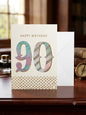 90th birthday card with pastel glitter numerals in teal lilac and pink with gold dot border and white envelope