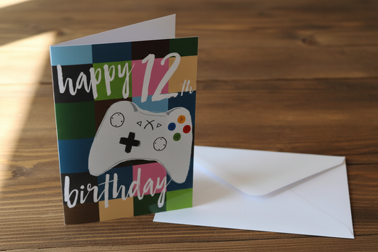 Happy 12th Birthday gaming controller card standing upright spine-left slightly open in a cosy lifestyle setting