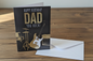 Happy Birthday Dad You Rock guitar card standing upright spine-left slightly open in a cosy lifestyle setting
