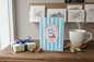 Happy Purrday cat birthday card styled on a rustic wooden surface with a wrapped gift, dried flowers and a cup of tea