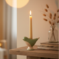 Sage green ceramic bird candle holder with lit taper candle in a cosy home setting