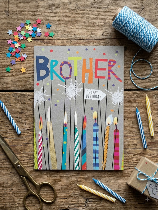 Brother Happy Birthday card with colourful birthday candles and sparklers on a grey kraft background with multicoloured lettering, styled on a rustic wooden table with confetti and birthday candles