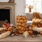 Pumpkin embossed amber ceramic vase styled with dried autumnal stems in a cosy home interior