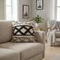 Scandi boho black and cream geometric tufted cushion on a light linen sofa in a cosy scandi interior