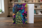 Happy Birthday peacock tropical card standing upright spine-left slightly open in a cosy lifestyle setting