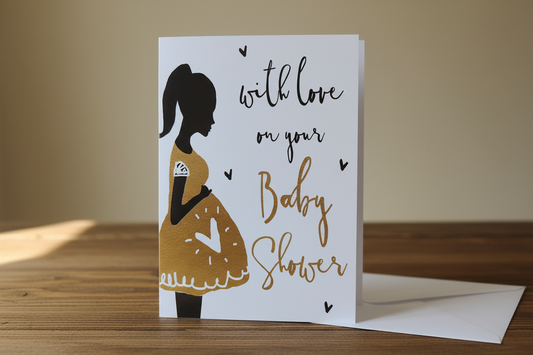 Baby shower gold silhouette card standing upright spine-left slightly open in a cosy lifestyle setting